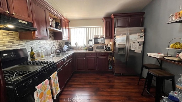 kitchen with decorative backsplash, dark wood-type flooring, under cabinet range hood, black appliances, and a sink