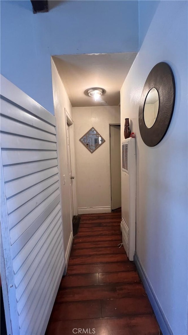 hallway featuring dark wood finished floors and baseboards