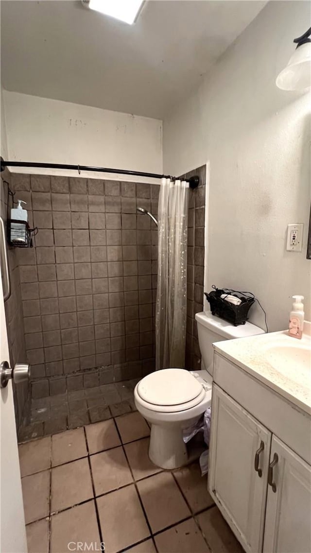 full bathroom with tiled shower, tile patterned flooring, vanity, and toilet