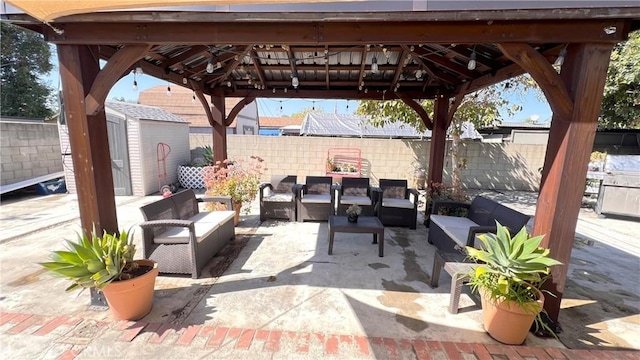 view of patio / terrace with an outbuilding, a storage unit, outdoor lounge area, a gazebo, and a fenced backyard