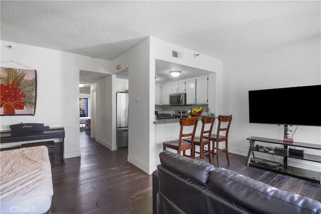 living room featuring visible vents, baseboards, a textured ceiling, and dark wood-style floors