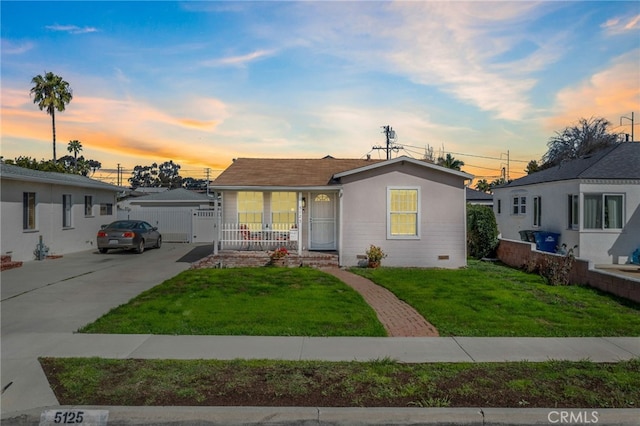 view of front facade with a lawn, concrete driveway, crawl space, covered porch, and fence