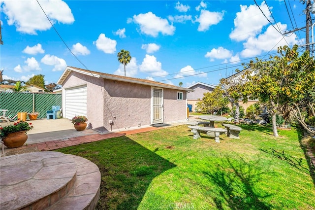 back of property featuring an outbuilding, a yard, stucco siding, a patio area, and fence