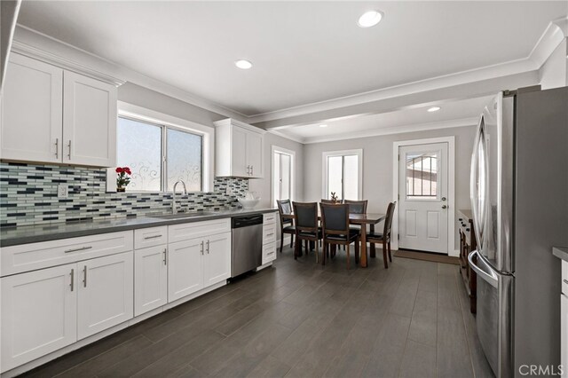 kitchen featuring dark wood-style flooring, dark countertops, backsplash, appliances with stainless steel finishes, and a sink