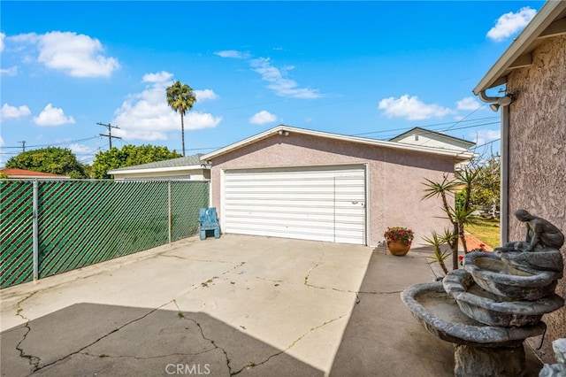 garage with concrete driveway and fence