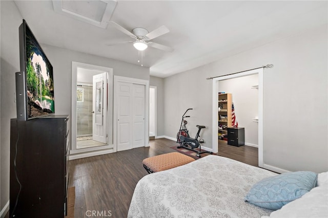 bedroom with dark wood-style flooring, a ceiling fan, baseboards, ensuite bath, and attic access