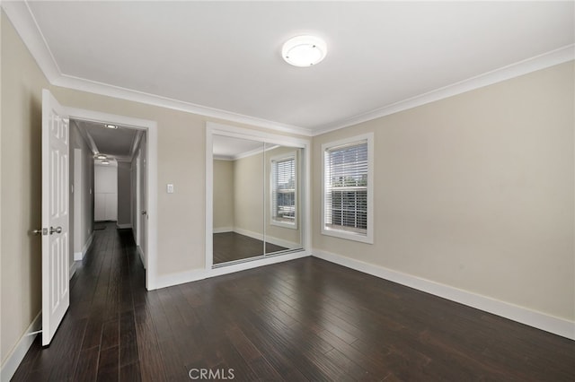 spare room featuring baseboards, ornamental molding, and dark wood-style flooring