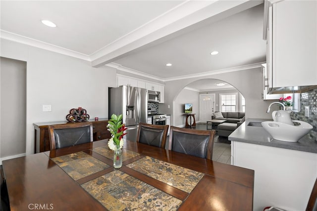 dining area featuring arched walkways, recessed lighting, and crown molding