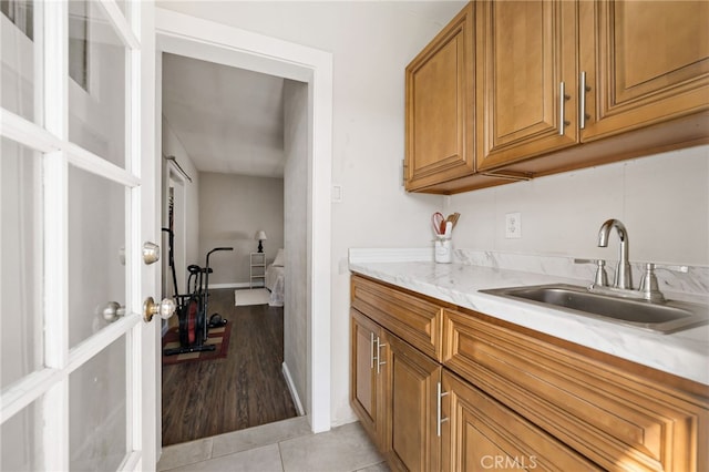 kitchen with light stone countertops, brown cabinets, a sink, and light tile patterned floors