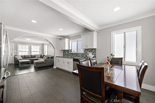 dining area with crown molding, arched walkways, dark wood-type flooring, and recessed lighting