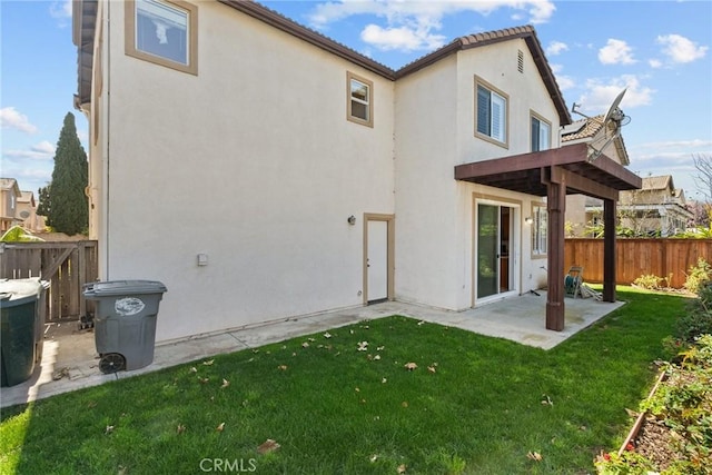 back of house with stucco siding, fence, a lawn, and a patio