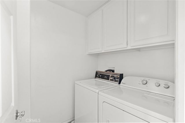 clothes washing area with washing machine and dryer and cabinet space