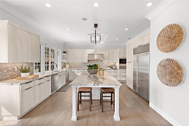 kitchen featuring ventilation hood, stainless steel appliances, a kitchen breakfast bar, modern cabinets, and a center island