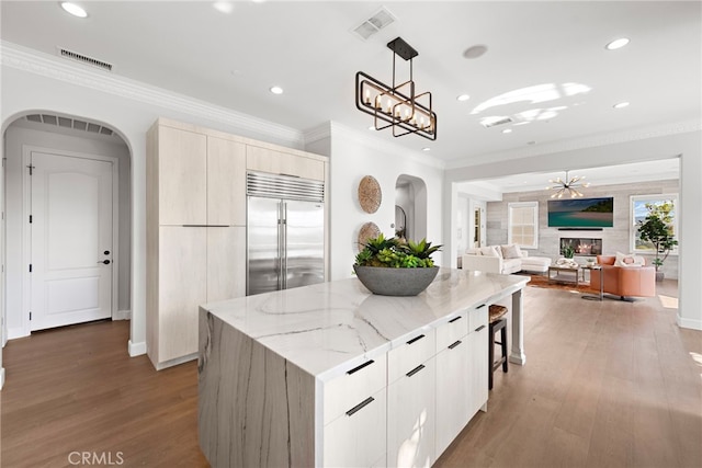 kitchen featuring arched walkways, visible vents, built in refrigerator, and modern cabinets