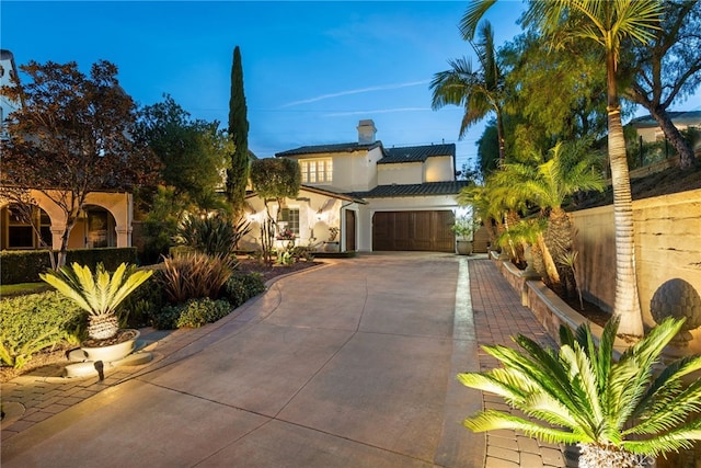 mediterranean / spanish home featuring stucco siding, a chimney, and driveway