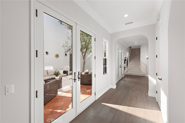 entryway featuring stairway, wood finished floors, visible vents, arched walkways, and ornamental molding