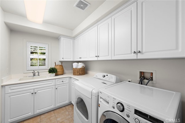 laundry area with visible vents, light tile patterned flooring, cabinet space, independent washer and dryer, and a sink