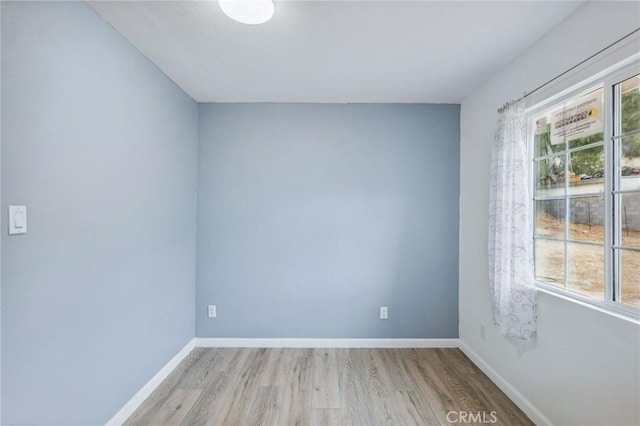 spare room with baseboards and wood finished floors