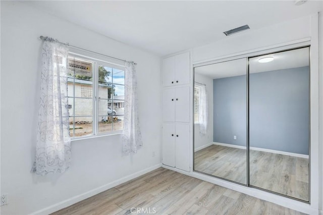 unfurnished bedroom with light wood-style flooring, baseboards, and a closet