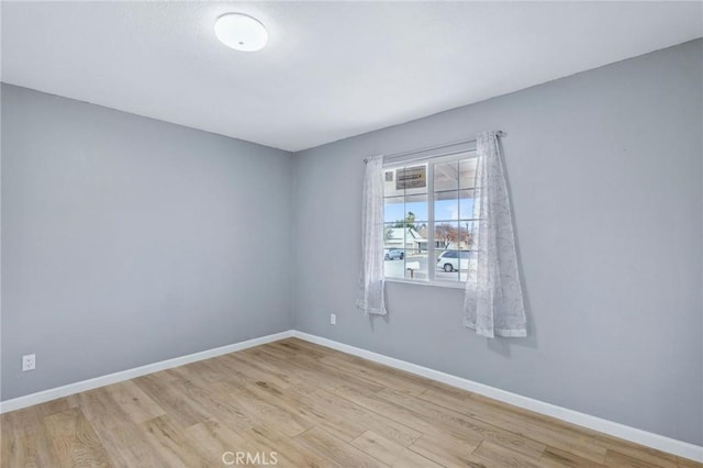 spare room with baseboards and wood finished floors