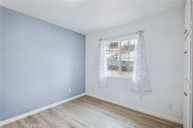 spare room featuring light wood-style flooring and baseboards