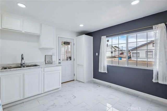 kitchen with marble finish floor, white cabinets, and a sink