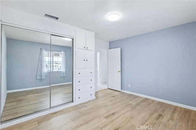 unfurnished bedroom with light wood-style floors, a closet, and baseboards