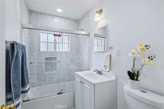 bathroom featuring combined bath / shower with glass door, vanity, and toilet