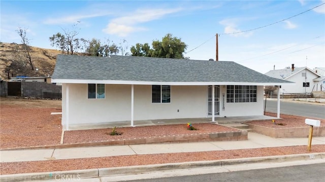 single story home with covered porch, roof with shingles, and stucco siding