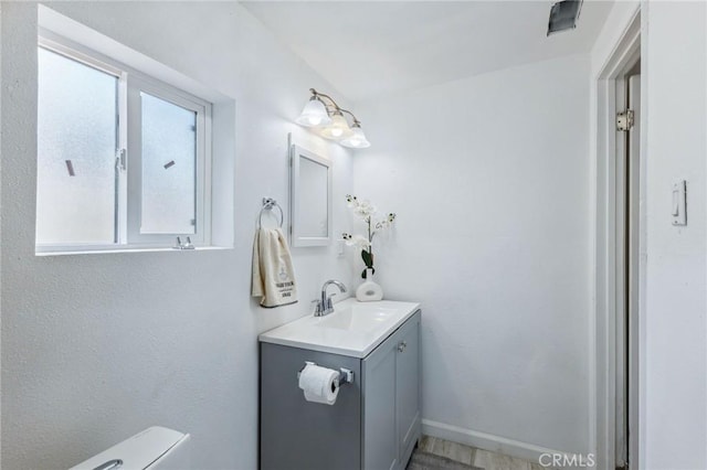 half bathroom featuring toilet, vanity, and baseboards