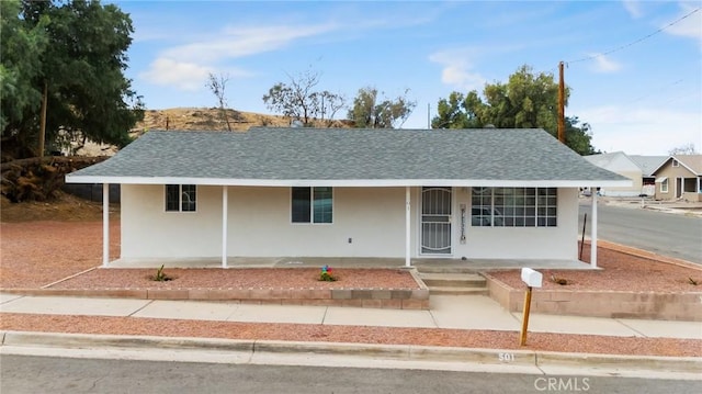 ranch-style house with covered porch, a shingled roof, and stucco siding