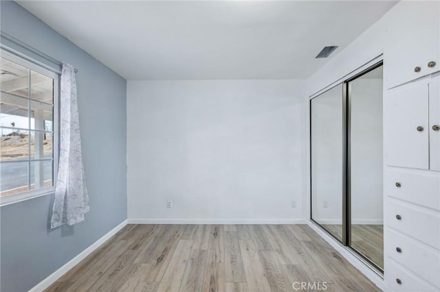 unfurnished bedroom with a closet, light wood-style flooring, and baseboards