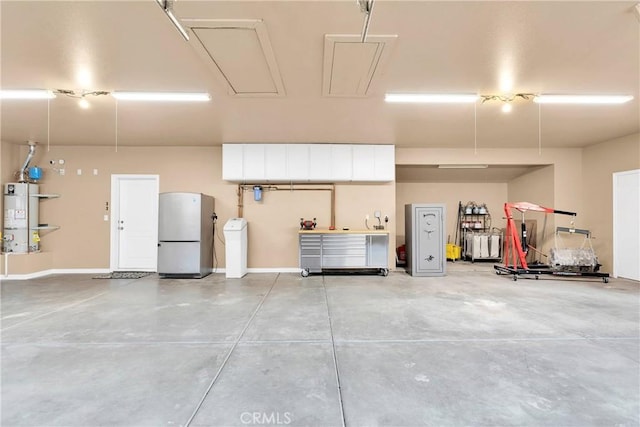 garage featuring freestanding refrigerator, secured water heater, and baseboards