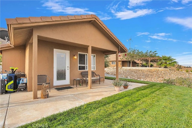 back of house featuring a yard, a patio, and stucco siding