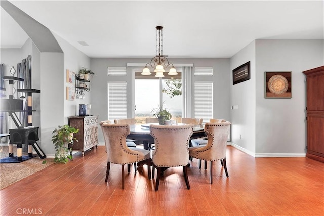 dining space featuring baseboards, an inviting chandelier, and wood finished floors