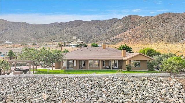 view of front of home featuring a chimney, a mountain view, and a front yard