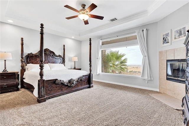 carpeted bedroom with a tile fireplace, a raised ceiling, visible vents, and baseboards