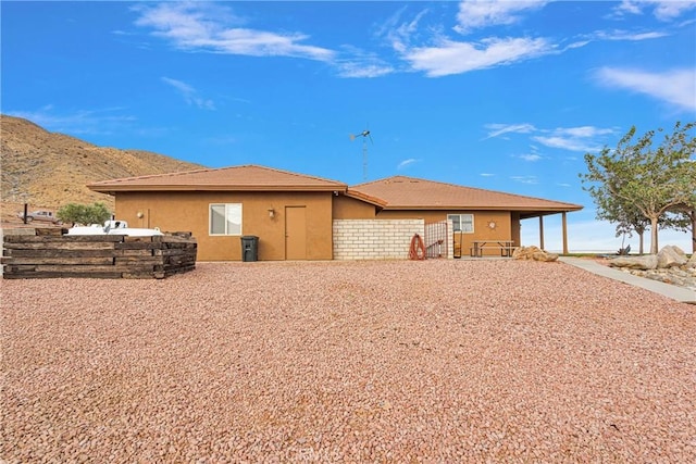 back of property featuring a mountain view and stucco siding