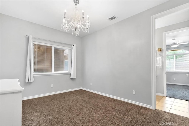 empty room with carpet, tile patterned floors, visible vents, baseboards, and ceiling fan with notable chandelier