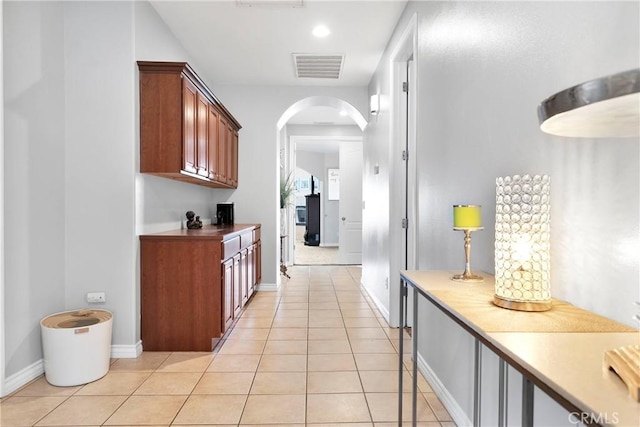 hall with arched walkways, recessed lighting, visible vents, light tile patterned flooring, and baseboards