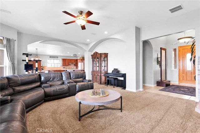 living area featuring arched walkways, light tile patterned floors, recessed lighting, light carpet, and visible vents