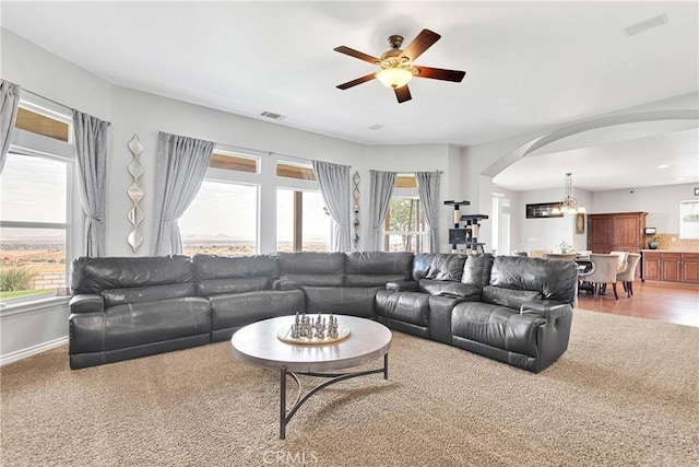 living room featuring arched walkways, ceiling fan, visible vents, and baseboards