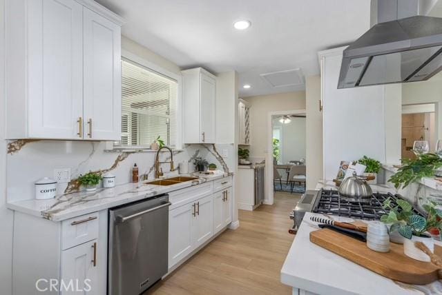 kitchen with dishwasher, wall chimney range hood, a sink, and a healthy amount of sunlight