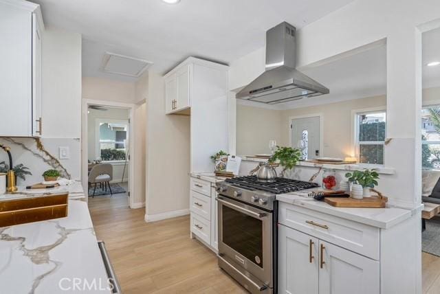 kitchen with white cabinets, light wood-type flooring, light stone countertops, range hood, and high end stove