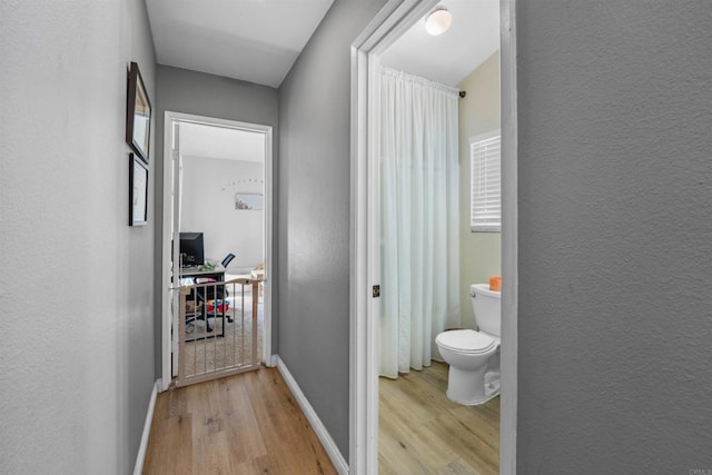 interior space with light wood finished floors, baseboards, and a textured wall