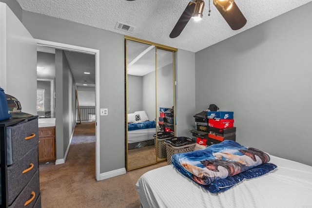 carpeted bedroom featuring baseboards, visible vents, ceiling fan, a textured ceiling, and a closet