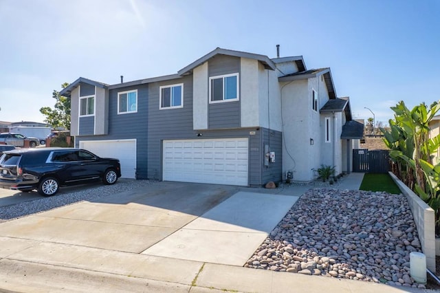 view of front facade featuring an attached garage, driveway, fence, and stucco siding