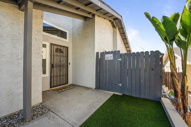 doorway to property with fence and stucco siding