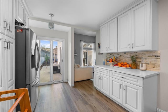 kitchen with light wood-style flooring, white cabinetry, stainless steel refrigerator with ice dispenser, and backsplash