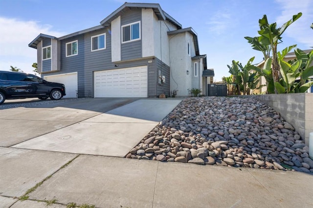 view of side of property with driveway, an attached garage, and fence